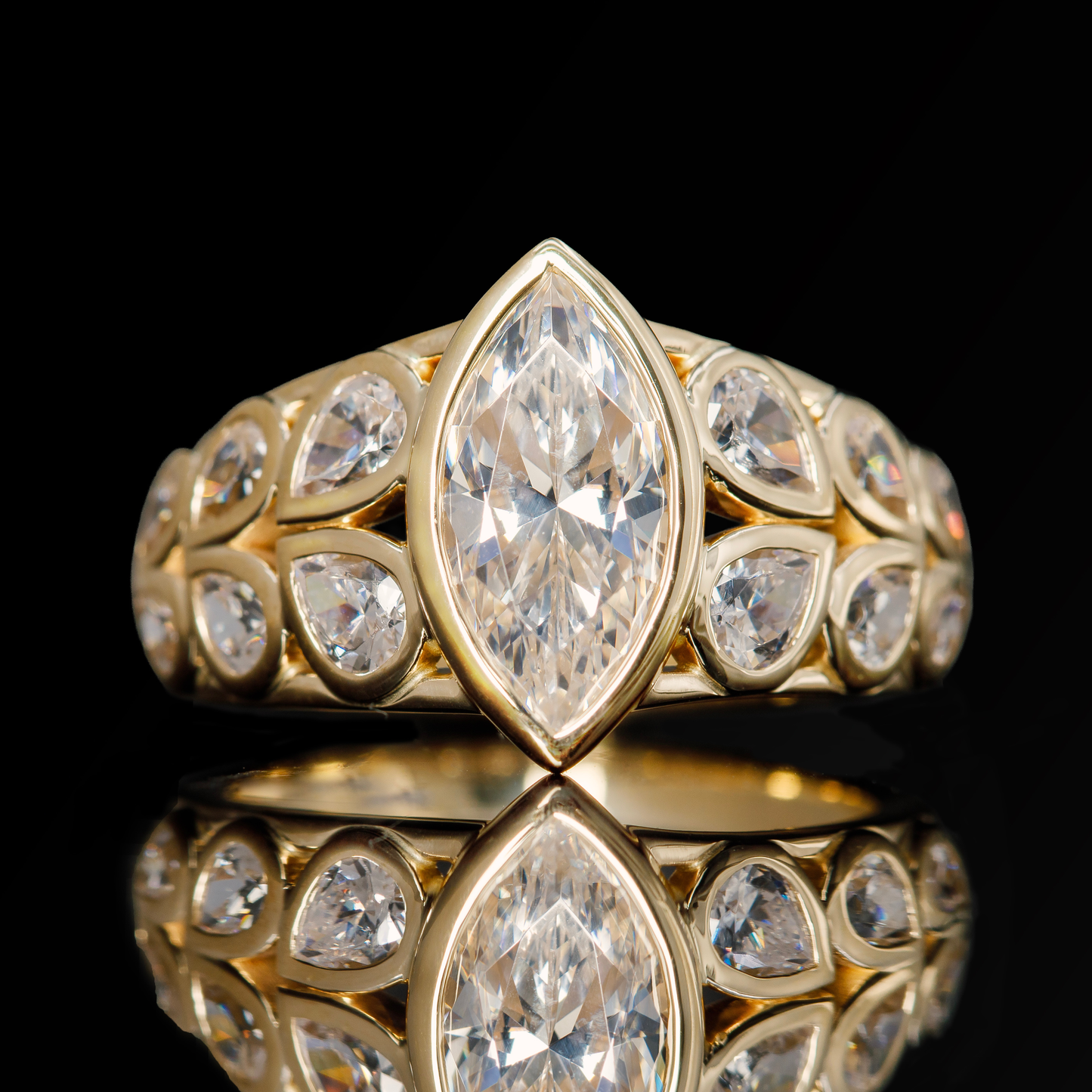 bezel set marquise diamond ring with yellow gold bezels and pear cut side stones
