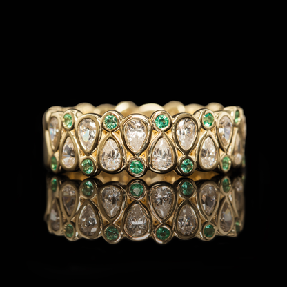 Pear cut eternity wedding band with emerald accents