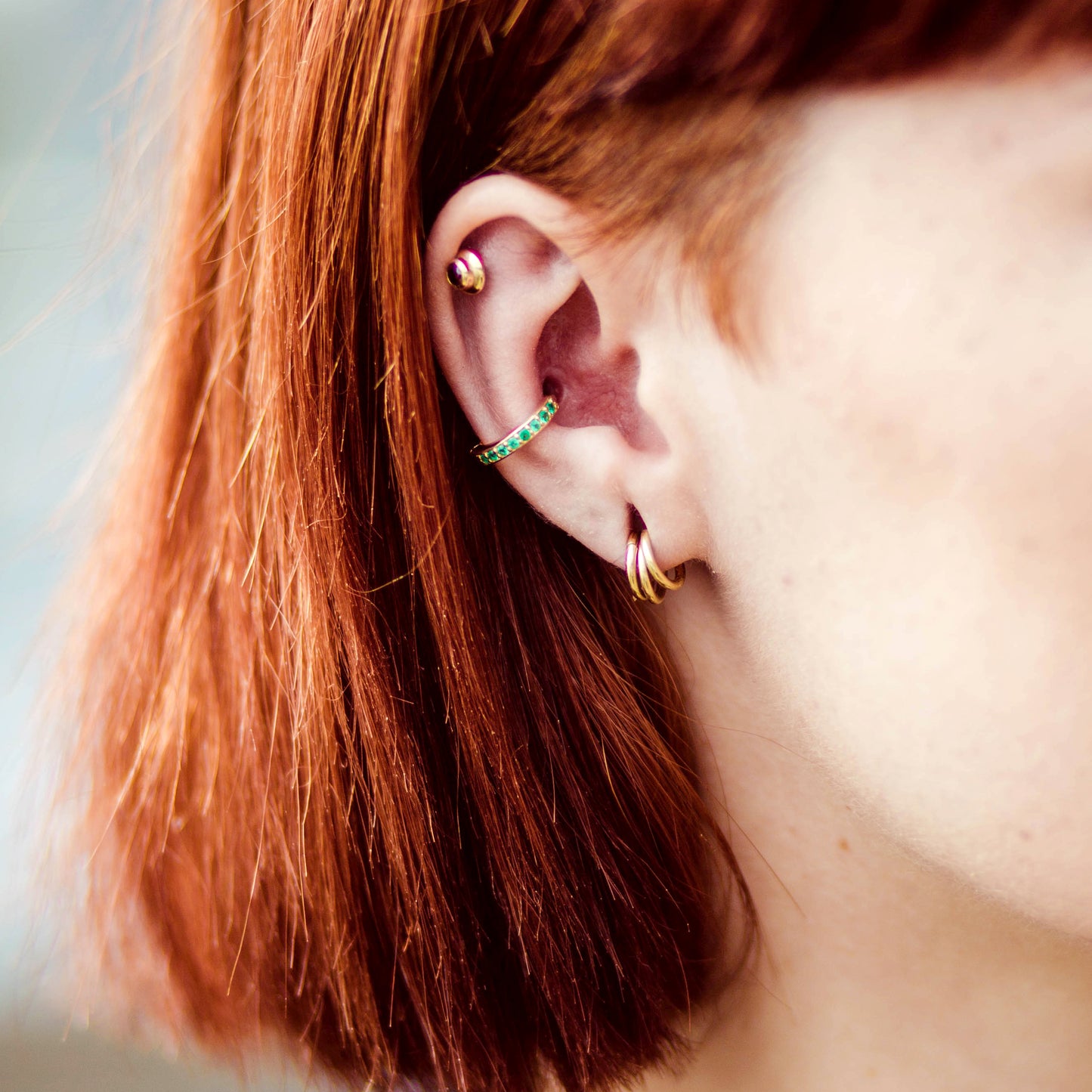 yellow gold conch piercing with emeralds