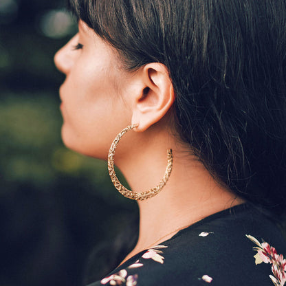 Gold hoop earrings being worn by a women. 