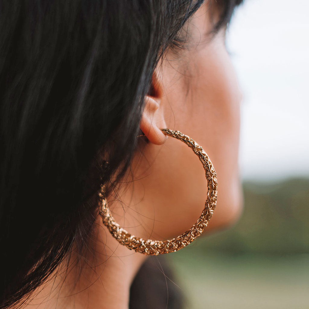 A women with dark brown hair wearing gold hoop earrings.
